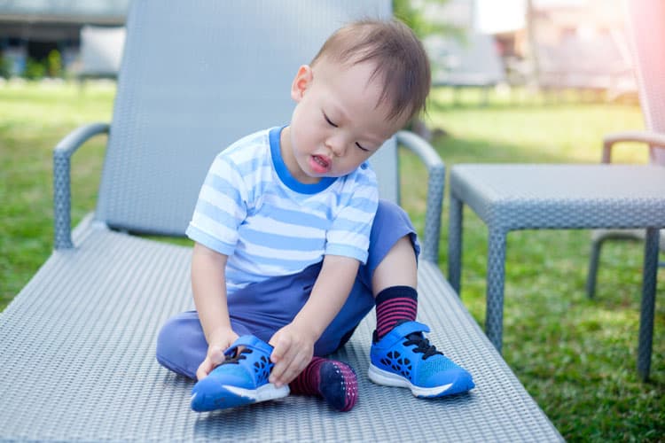 Little Boy Putting On Shoes