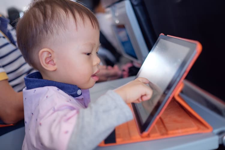 Child Playing On Ipad In Airplane For Stress-Free Flying With Babies And Toddlers