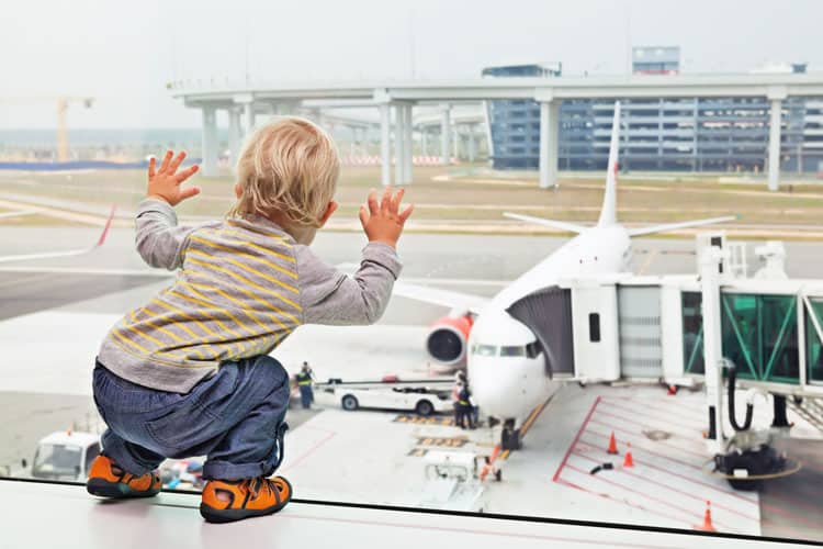 Little Boy Looking Out The Window Or Airport At A Popular Airline On Runway