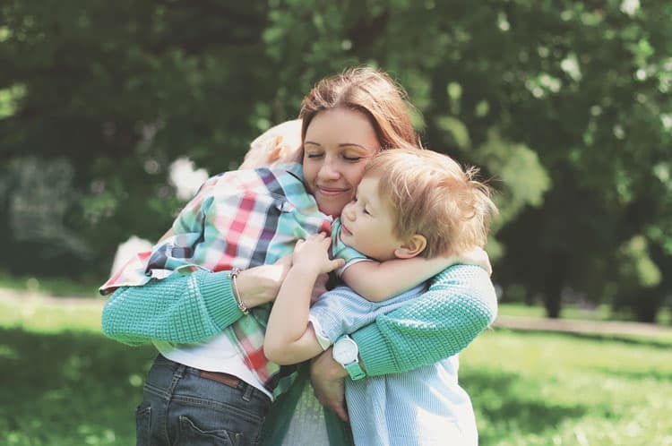 mother giving her two children a hug