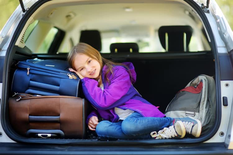Girl Sitting In The Trunk Of A Car With Luggage