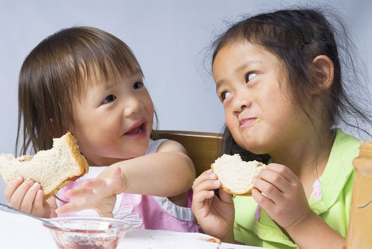 Two Girl Eating Peanut Butter Sandwiches