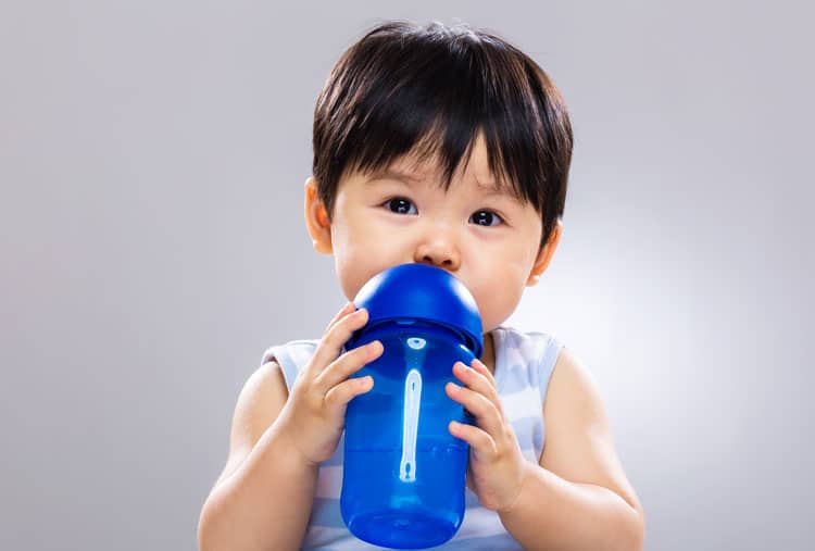 Little Boy Drinking Water Out Of A Water Bottle