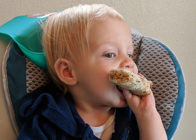 baby eating a peanut butter sandwich for healthy travel snack