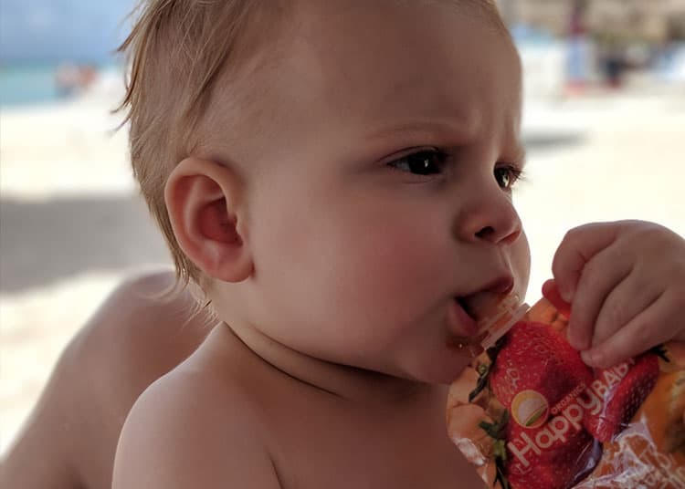 baby eating fruit squeeze as a tasty travel snack