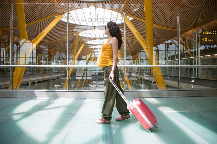 Expecting Mother In The Airport With Suitcase