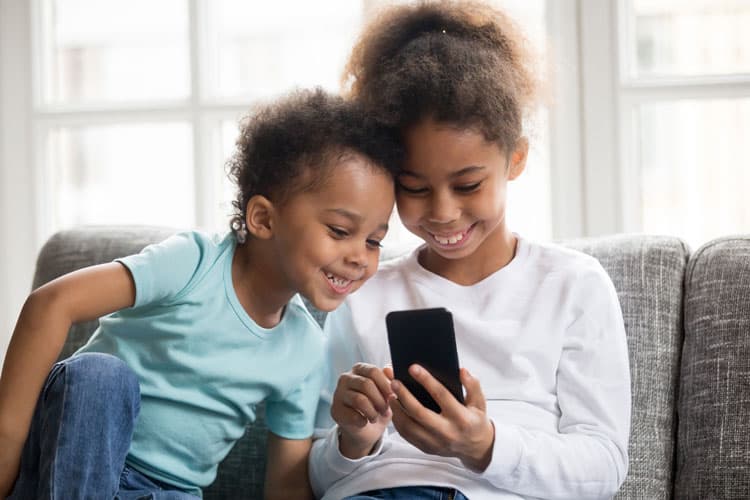 Two Children Looking At Mobile Phone