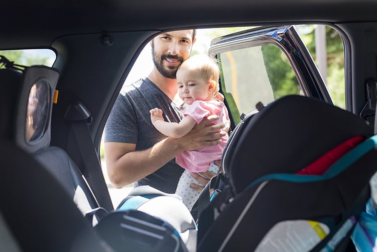 Father Putting Baby In A Car Seat
