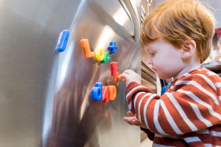 boy playing with magnets on the refrigerator