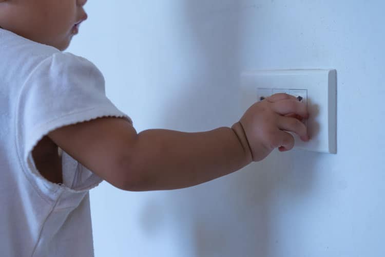 baby dangerously playing with electrical outlet