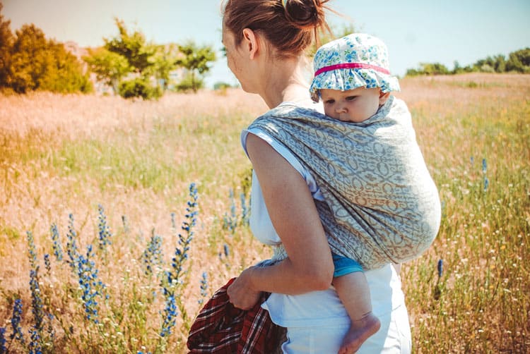 Mother Walking Through Field With Baby On Back