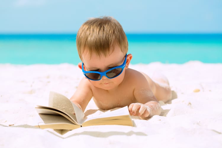 Child Reading A Book On The Beach